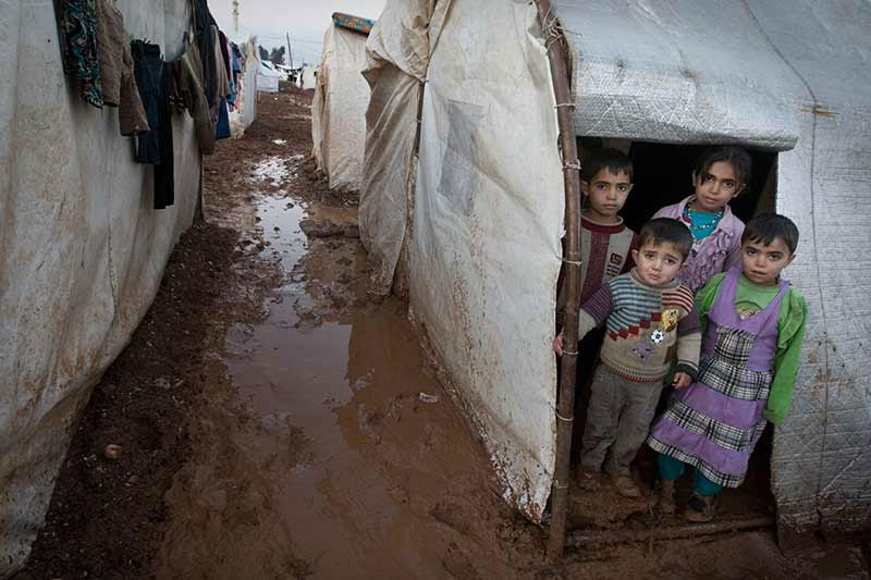 Syrian children stand in the entryway of their tent shelter in the Bab Al Salame camp for internally displaced persons in Aleppo Governate. (Photo: UNICEF/Giovanni Diffidenti)
